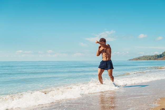 Um muay thai ou kickboxer treinando com boxe de sombra ao ar livre na praia