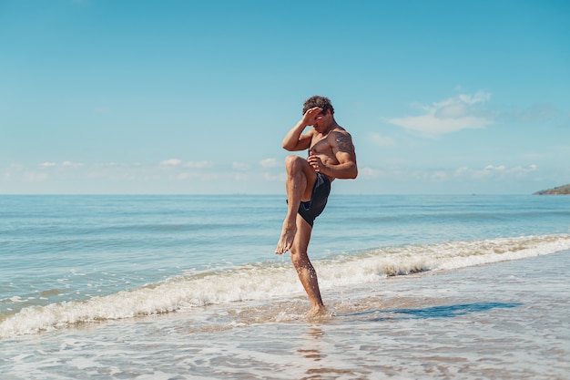 Um muay thai ou kickboxer treinando com boxe de sombra ao ar livre na praia