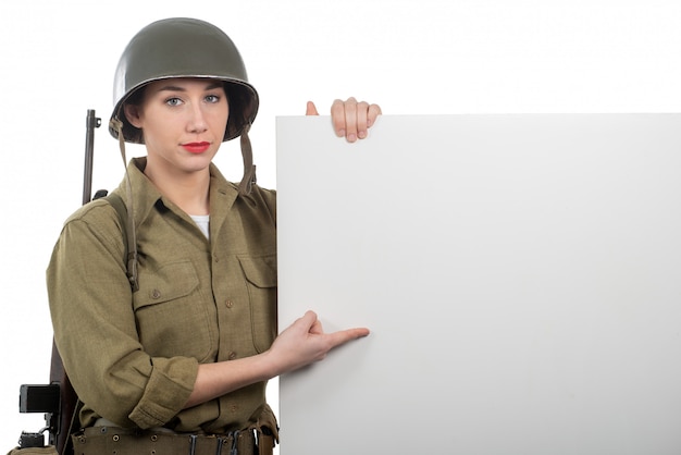 Foto um, mulher jovem, vestido, em, americano, ww2, uniforme militar, mostrando, vazio, em branco, signboard