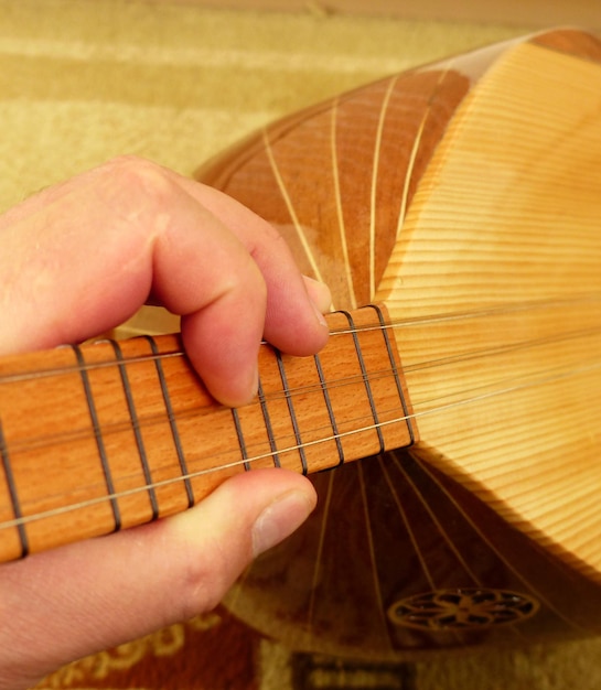 Um músico está segurando um saz instrumentos musicais turcos closeup baglama saz