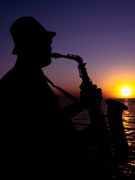 Um músico tocando saxofone ao pôr do sol