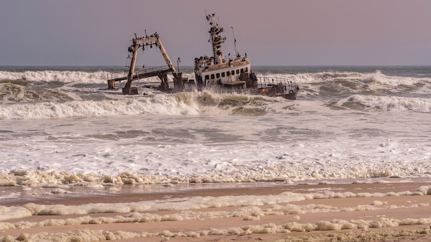 Um naufrágio encalhado na praia no oceano atlântico no parque nacional da costa do esqueleto na namíbia, áfrica.