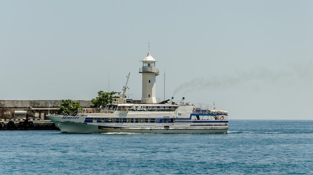 Um navio a vapor branco no porto perto do farol.