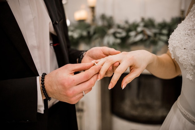 Um noivo e uma noiva vestem alianças de casamento um para o outro