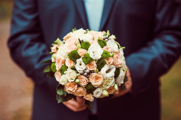 Um noivo elegante com um buquê de casamento nas mãos