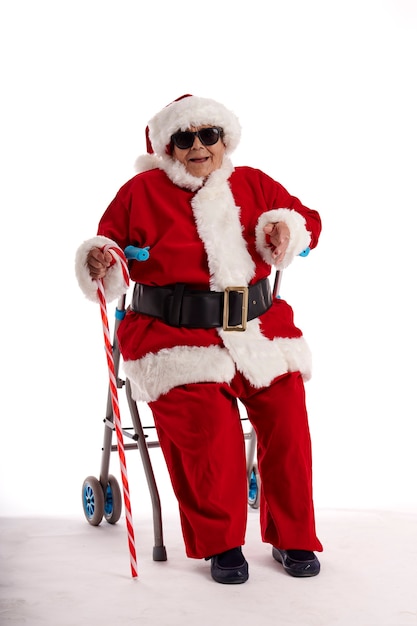 Um nonagenário fantasiado de Papai Noel, sentado em um andador com um fundo branco.