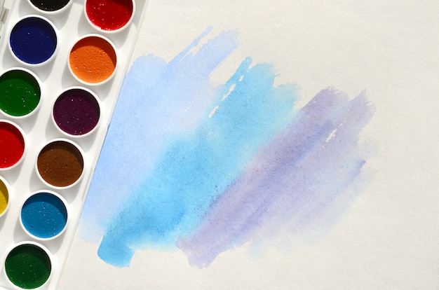 Um novo conjunto de aquarelas encontra-se em uma folha de papel, que mostra um desenho abstrato de aquarela na forma de traços azuis