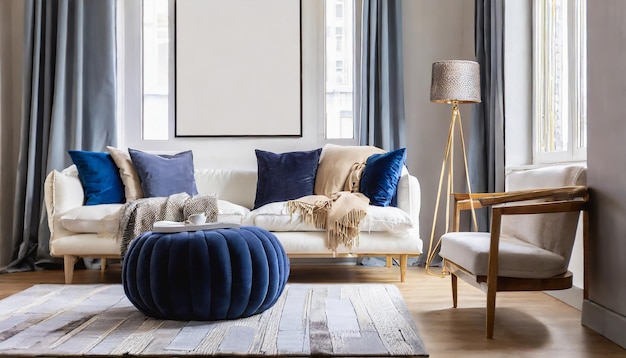 Um ottoman azul marinho perto de um sofá branco com um cobertor bege contra a janela e uma parede branca com um quadro grande...