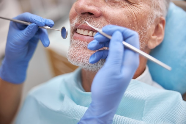 um paciente sênior sorrindo enquanto examina seus dentes