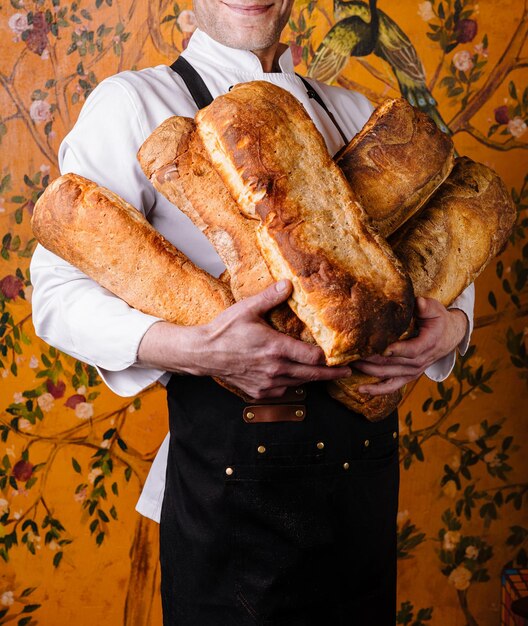 Foto um padeiro artesanal segurando pães recém-cozidos