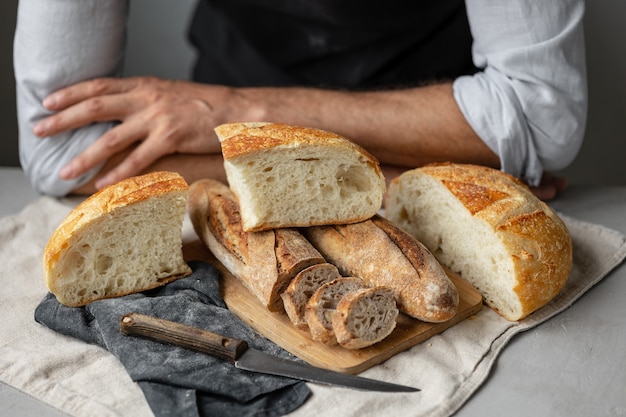 Um padeiro europeu adulto segura um pão fresco redondo nas mãos, um homem em uma padaria segura um