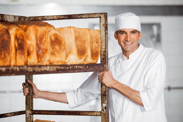 Um padeiro maduro ao lado de uma prateleira de pão