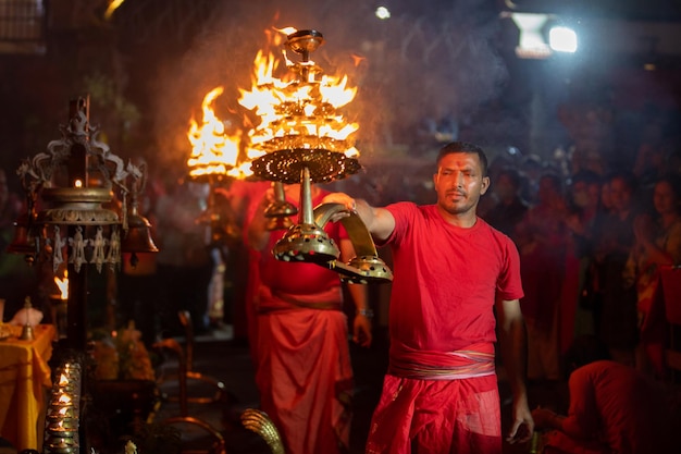 Um padre nepalês realizando o arati da noite nas instalações da praça Durbar de Basantapur