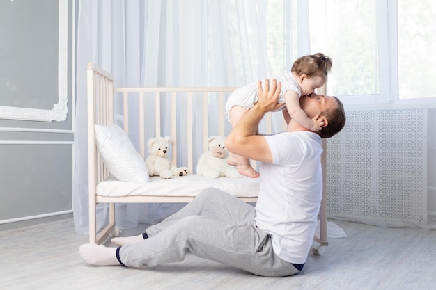 Um pai beija sua filha bebê no quarto do berçário feliz dia dos pais da família