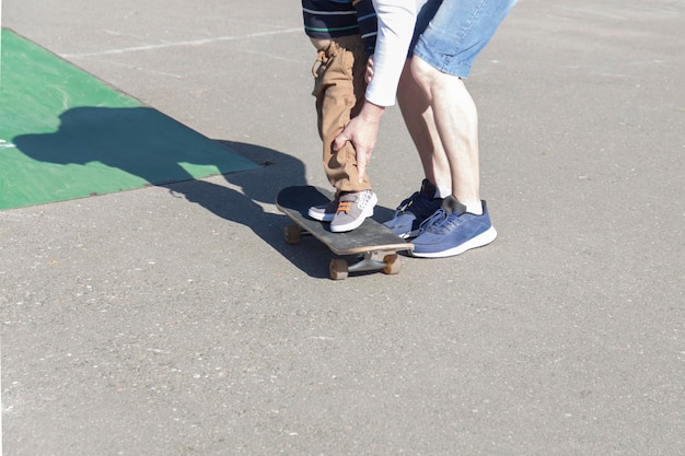 Um pai carinhoso e amoroso ensina seu filho de três anos a andar de skate