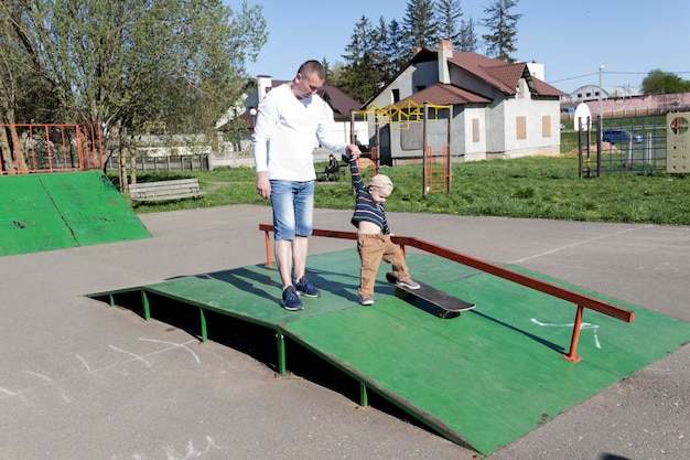 Um pai carinhoso e amoroso ensina seu filho de três anos a andar de skate