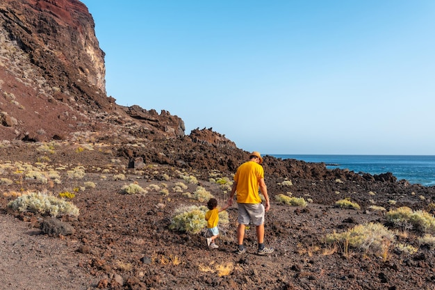 Um pai com seu filho caminhando por um caminho vulcânico na praia de Tacoron em El Hierro Ilhas Canárias