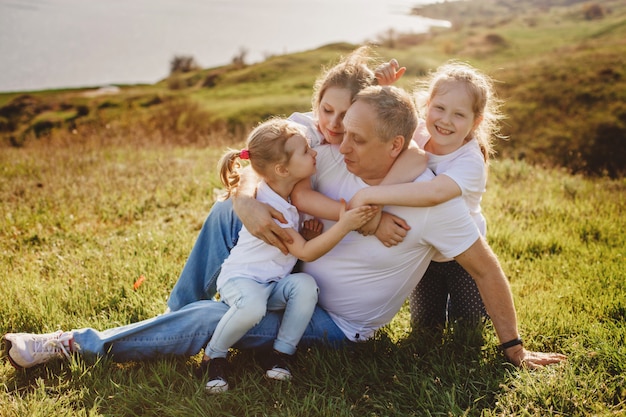 Um pai com três filhas senta-se na grama