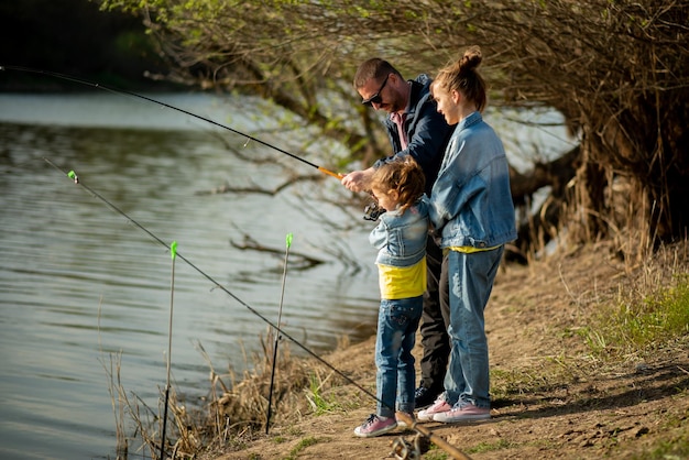 Um pai e suas duas filhas estão pescando no rio Passatempo de férias em família