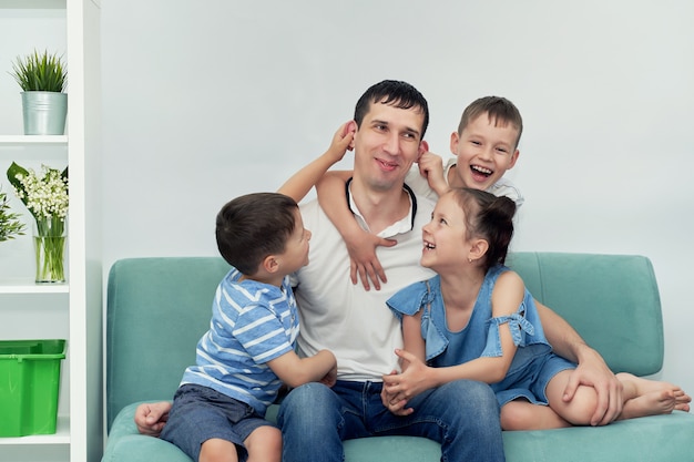 Um pai feliz com muitos filhos e seus filhos está sentado em um sofá azul