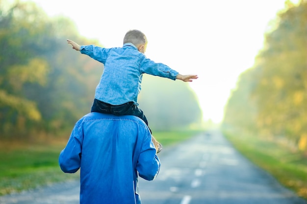 Um pai feliz com um filho caminhando pela estrada no parque em uma viagem pela natureza