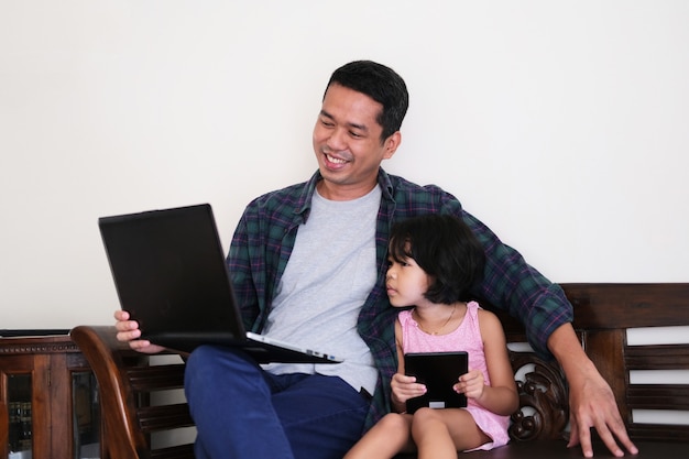 Um pai mostrando algo em um laptop para sua filha