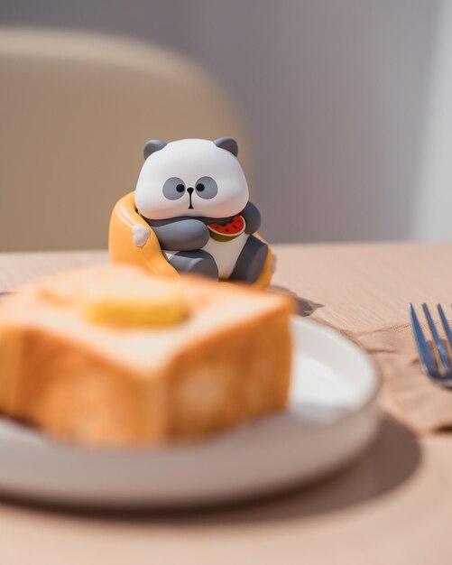 Foto um panda de brinquedo mudando sua atenção para a deliciosa torrada na frente dele