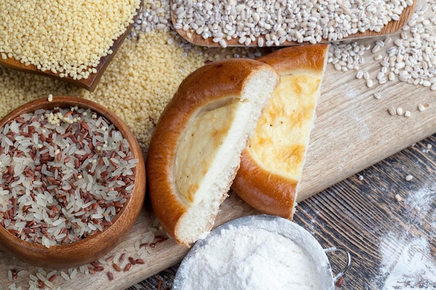 Um pão usando creme azedo em uma tábua com alimentos de grãos de cevada pérola em cima da mesa