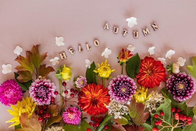 Um papel de parede de cartão festivo um fundo de outono de flores de jardim cortadas coloridas texto de conceito floral feito de letras de madeira olá outono