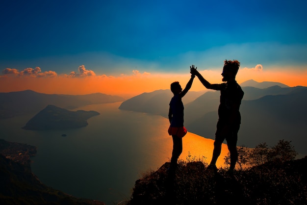 Um par apertar as mãos na vitória no topo de uma montanha