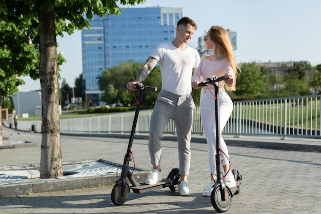 Um par atraente de amantes monta scooters elétricos e olha um para o outro