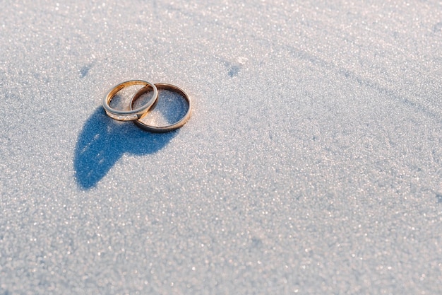 Um par de alianças de casamento de ouro na neve Duas alianças de casamento