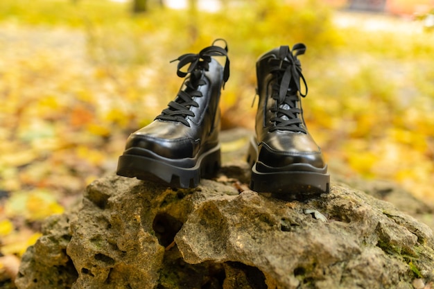 Foto um par de botas pretas está sobre uma pedra na floresta.