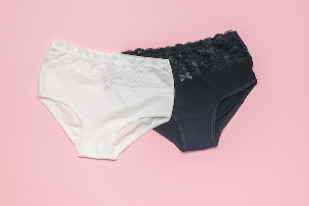 Um par de lindas calcinhas femininas em um fundo rosa claro Conceito mínimo de roupas íntimas femininas