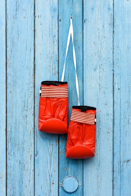 Um par de luvas de boxe de couro vermelho pendurado em um cordão branco
