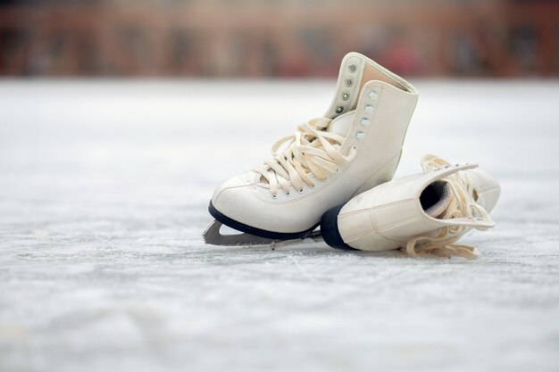 Um par de patins brancos encontra-se em uma pista de gelo aberta