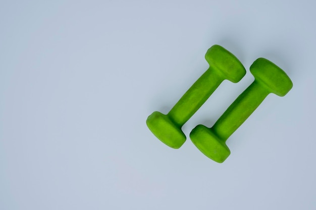 Um par de pequenos halteres verdes claros em um estilo de vida saudável de fitness de fundo branco