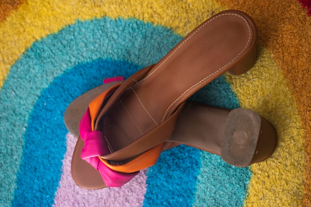 Foto um par de sandálias marrons com um laço de fita rosa no topo.
