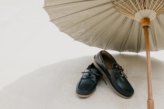 Um par de sapatos com um guarda-chuva branco no chão