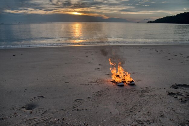 um par de tênis em chamas deixados na praia