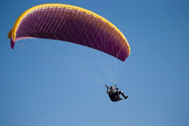 Um parapente voa no céu sob um parapente multicoloridoHomem sob paraquedas