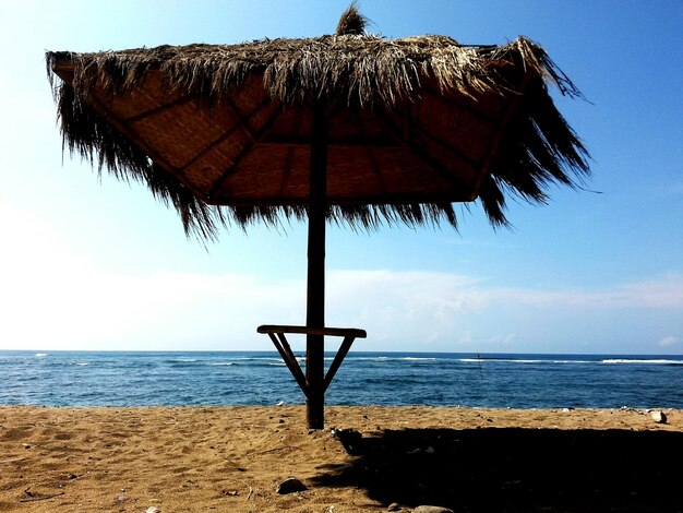 Foto um parasol de telhado de palha na costa na praia contra o céu