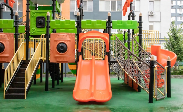 Um pátio de prédios altos com um novo e moderno playground colorido e grande em um dia chuvoso de verão sem pessoas. Parque infantil vazio ao ar livre. Um espaço para jogos e esportes infantis.