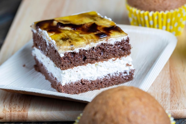 Um pedaço de bolo de banana e sobremesa de banana fatiada fresca de creme de manteiga de pão de ló doce com banana e recheio de banana