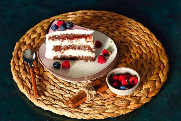 Um pedaço de bolo de biscoito de chocolate com recheio de creme de queijo em fundo azul escuro fecha bagas