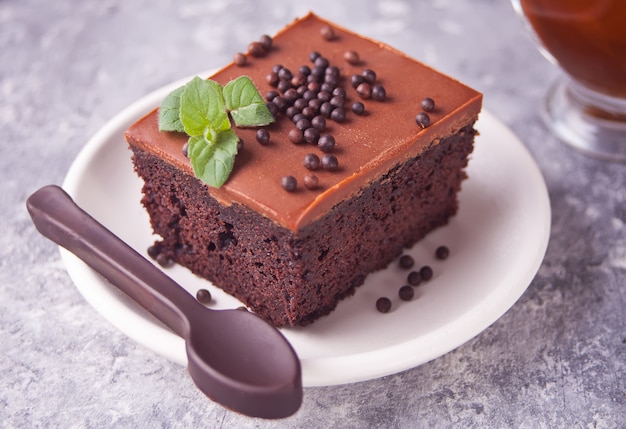 Um pedaço de bolo de chocolate caseiro no prato com cobertura, folha de hortelã e chocolate