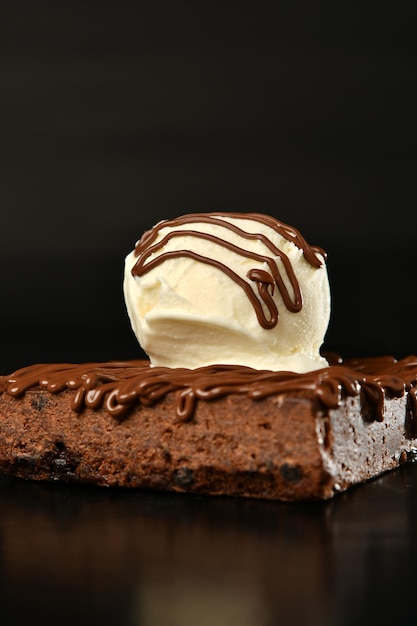 Um pedaço de bolo de chocolate com cobertura branca e gotas de chocolate por cima.