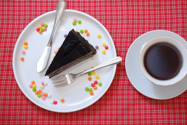 Um pedaço de bolo de chocolate num prato rosa numa mesa de mármore branco