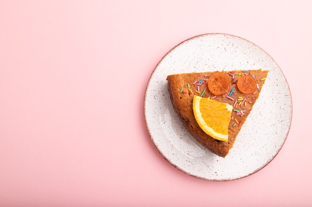 Um pedaço de bolo de laranja em um fundo rosa pastel. Vista superior, configuração plana, copie o espaço.