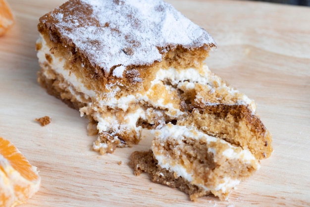 Um pedaço de bolo de mel com creme de baunilha e tangerinas cítricas